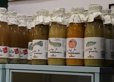 Primer plano de un expositor sobre el que vemos tarros de cristal con cremas de verduras