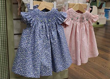 Vista del interior del comercio, dónde podemos ver dos vestidos, uno de colores azulados con flores estampadas y el otro de cuadros rosas y blancos