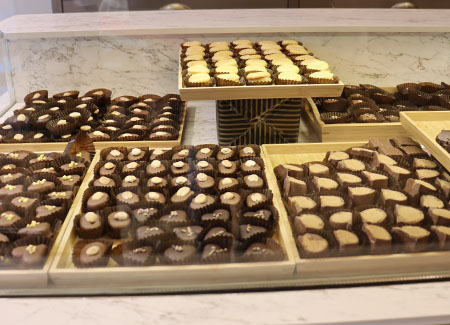 Vista de un expositor de bombones, dónde podemos ver siete bandejas con bombones de diferentes estilos y composiciones