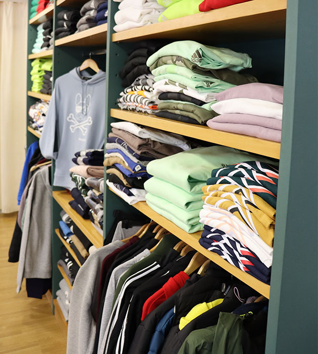 Vista interior del comercio, dónde podemos ver varias estanterías con ropa doblada o en perchas