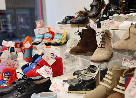 Primer plano del escaparate grande donde podemos ver varios zapatos y botas infantiles