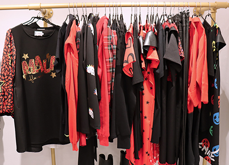 Un perchero de pared con diversas prendas de color rojo y negro colgada en perchas