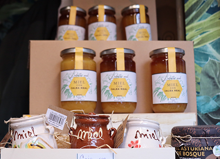 Primer plano de un expositor con tarros de miel de jarrea real y botes de cerámica con la palabra miel escrita en ellos