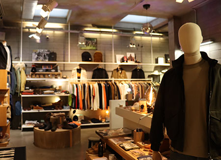 Vista del interior del comercio, donde podemos ver un maniquí en primer plano, con ropa de invierno, al fondo un perchero con baldas y una estantería en la pared con múltiples prendas y varios expositores con ropa y calzado en el plano medio