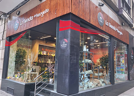 Vista del exterior de la tienda, dónde podemos ver hace esquina y que la entrada está en una de las calles. También podemos ver los tres grandes escaparates de la tienda